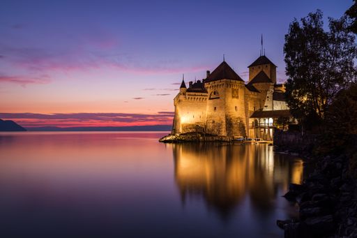 The famous and beautiful Chillon Castle reflecting in the Geneva Lake at sunset, in Veytaux Switzerland