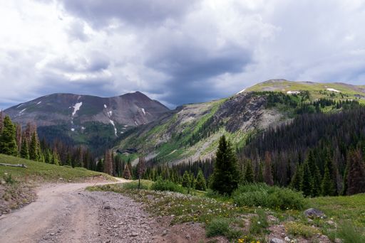 A beautiful view of a small road on the San Juan mountains under the blue partly cloudy sky