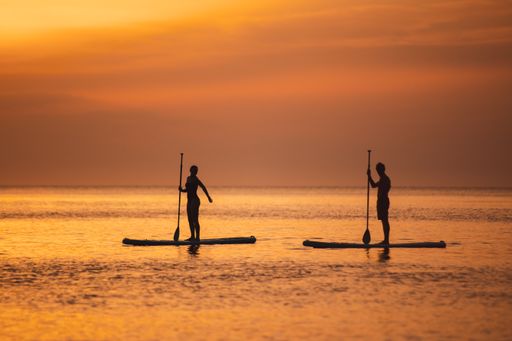 Two people sailing in the sea at sunset