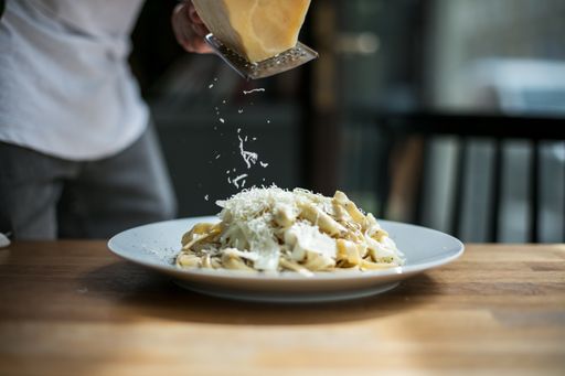 A Editorial of a restaurant setting with visible hands twirling pasta and plates at the table