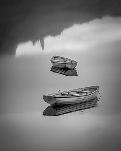 A beautiful grayscale shot of two small wooden boats in the reflective shiny gray water