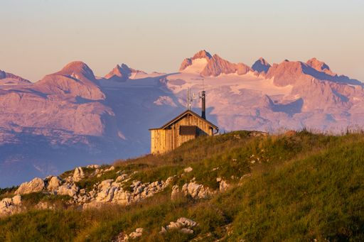 A beautiful shot of a wooden house in rocky green mountains