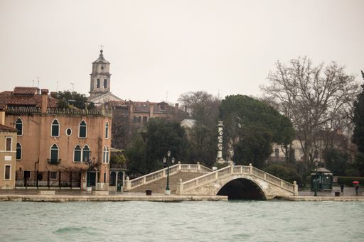 A beautiful view of old medieval buildings with church and a bridge over the river on a cloudy day