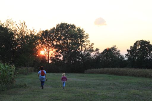 The two kids running in the field at sunset