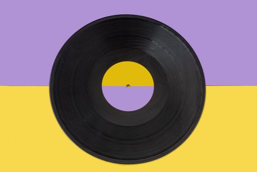 A closeup of a gramophone disc record on a yellow background