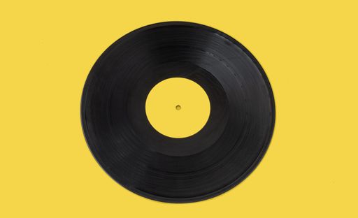 A closeup of a gramophone disc record on a yellow background