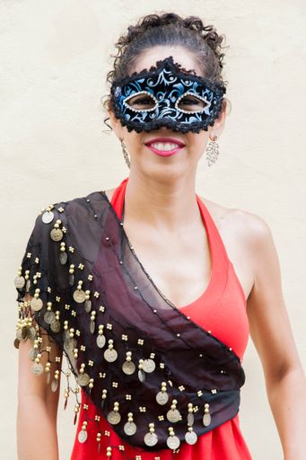 A Brazilian woman wearing Venice Carnival mask against a wall background in Brazil