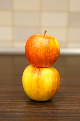 A selective focus shot of the apples on top of each other on a wooden surface