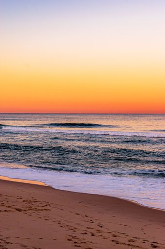 The calm waves rolling into the shore at the beach during sunset