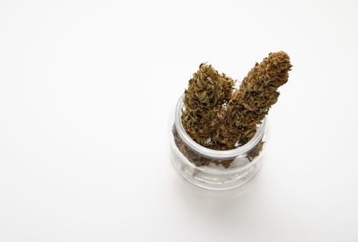 A closeup shot of cannabis in a glass jar isolated on a white background