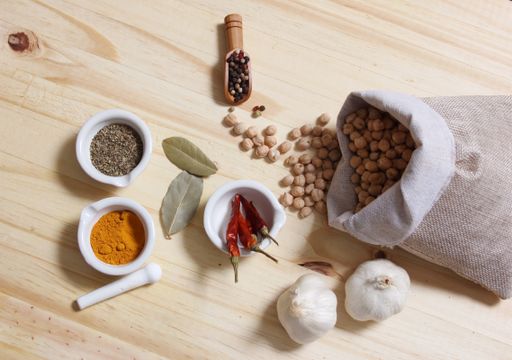 A bag of garbanzo beans with garlic and various spices on a wooden table