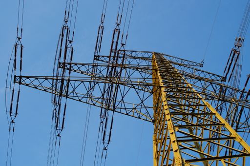 Silhouette of a high-voltage pylon in the blue evening sky. Boom with insulators.