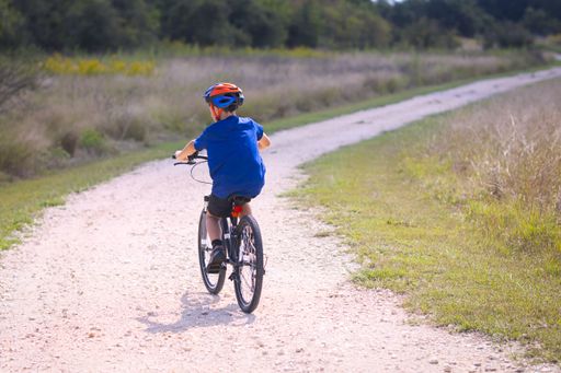 A beautiful shot of a kid riding a bike in a dirty trail
