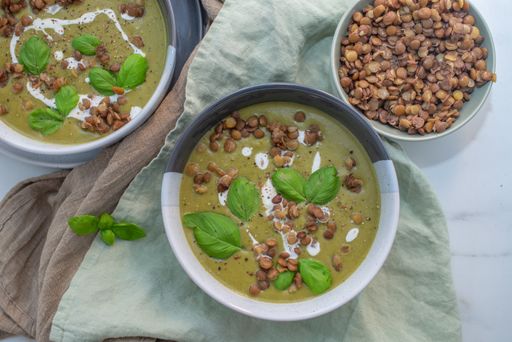 An overhead shot of bowls of lentil spinach soup with basil leaves
