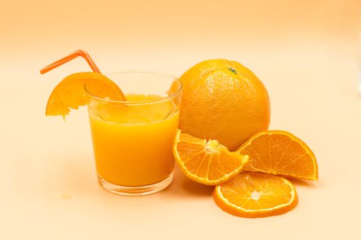 A closeup shot of sliced oranges and a glass with orange juice