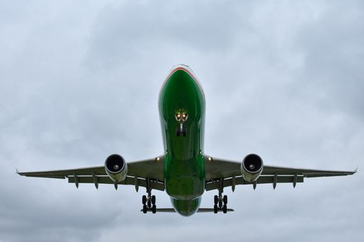 A low angle shot of a flying green plane in a cloudy sky