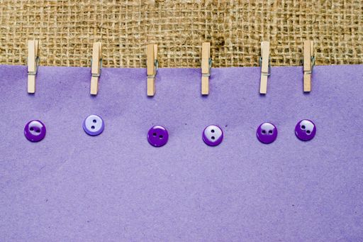 A closeup shot of a wooden clips with buttons on a lavender paper