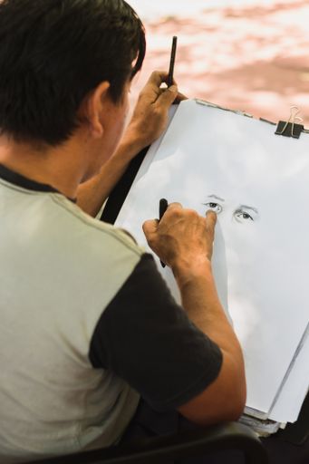 A vertical shot of an artist drawing a portrait