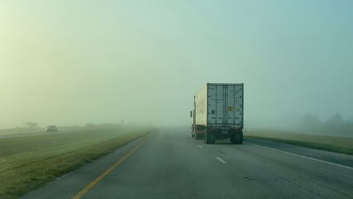 A truck on a highway in the fog