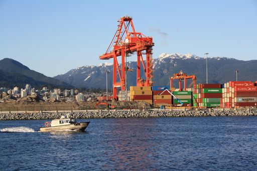 The Motor boat floating by cranes and containers in the Port of Vancouver. British Columbia, Canada