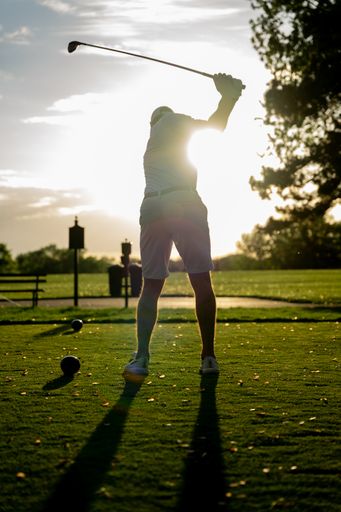 A golfer in backswing backlit by the sun