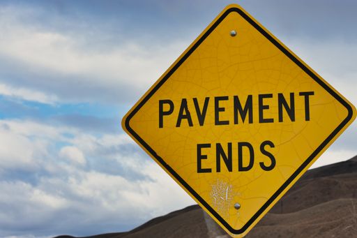 A closeup shot of the yellow "pavement ends" warning sign with bullet holes