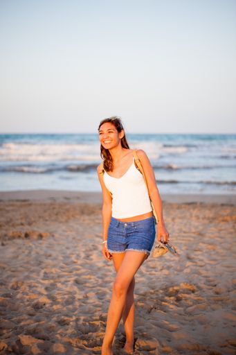 A vertical shot of a Caucasian woman walking near the water
