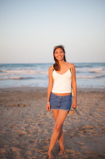 A vertical shot of a Caucasian woman walking near the sea