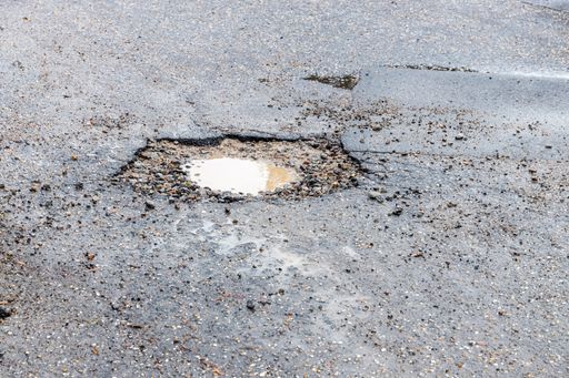 A small dirty pothole in a cement road