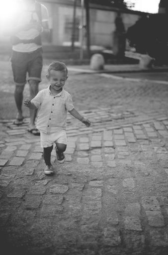 A grayscale vertical picture of a running happy caucasian kid