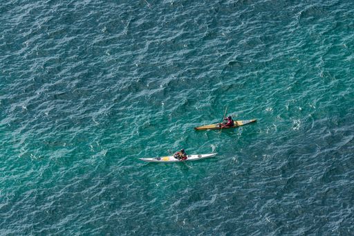 An aerial shot of two kayaks in the turquoise blue sea near the Cornwall coast