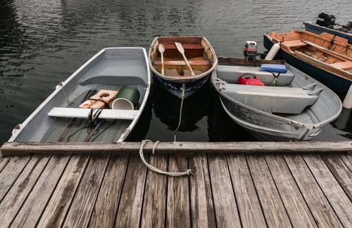 A bunch of boats tied to a wooden port near a lake