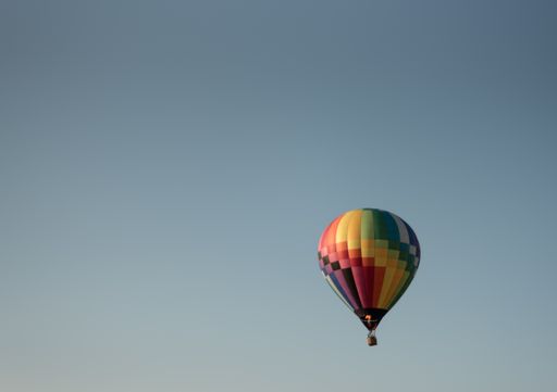 A floating colorful hot air balloon in a blue sky
