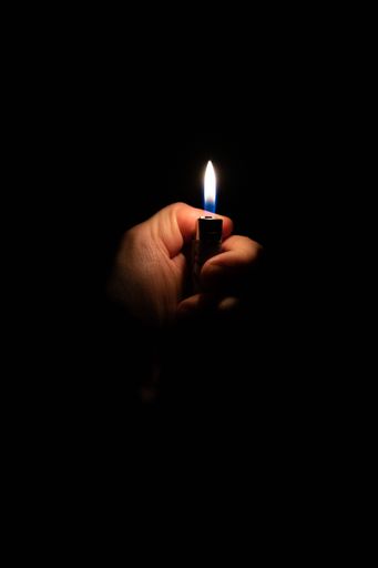 A hand holding a lighter on a black background