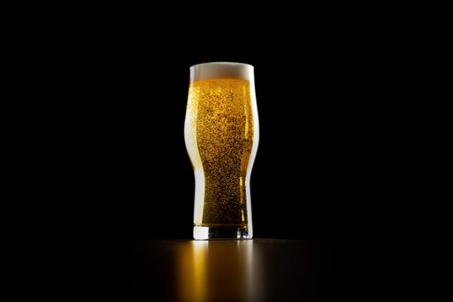 A Crisp Refreshing Ice Cold Golden Ale Craft Beer In Pint Glass Isolated on Black background