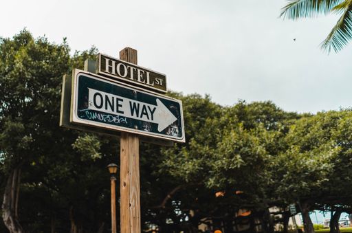 A beautiful shot of One Way Hotel Street Sign In Downtown Hawaii with trees and a light sky