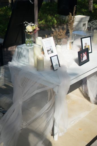 A closeup shot of a white table with photo frames decorated with candles and flowers for a wedding ceremony