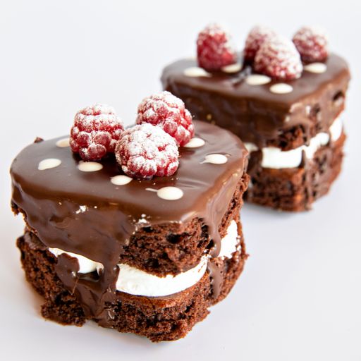 A closeup shot of two Chocolate cake pieces with raspberry on a white surface background