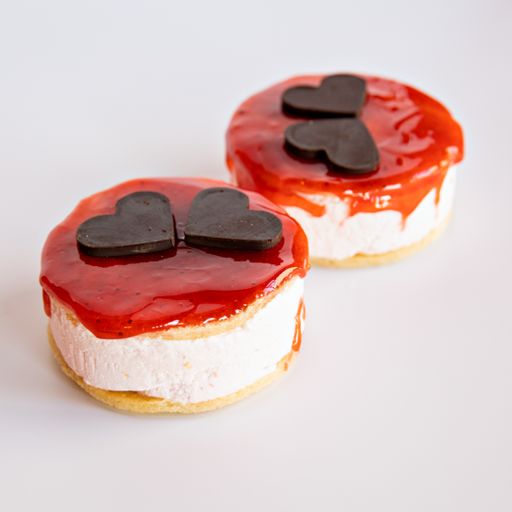 A closeup shot of two Cheesecake pieces with heart shape chocolate pieces on a white background