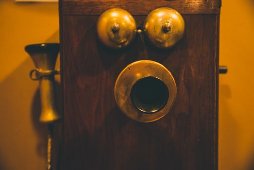 A closeup shot of a vintage brown telephone on an orange wall