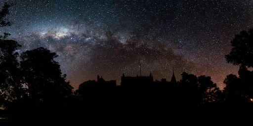 A beautiful panoramic shot of silhouettes of trees and buildings under a starry night