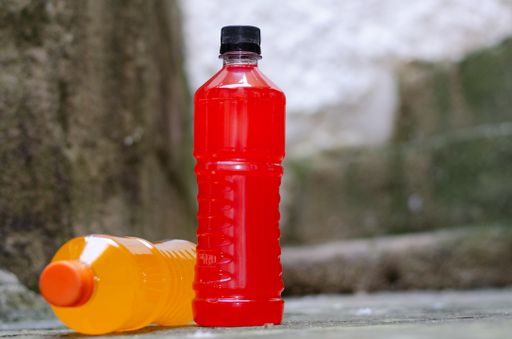 A shallow focus of a standing red Electric Energy Drink bottle and laying a yellow bottle