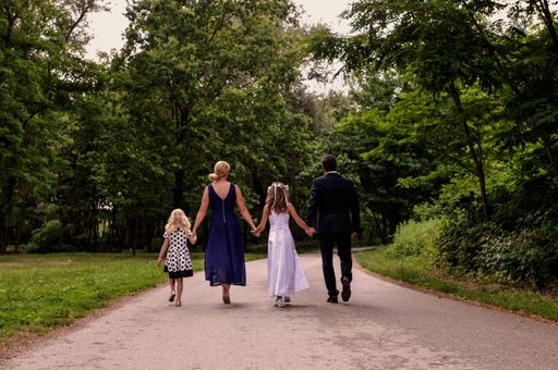 A happy family together, parents with their daughters walking through the beautiful forest