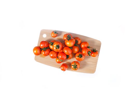 A top view of small red tomatoes on a wooden board on a white background
