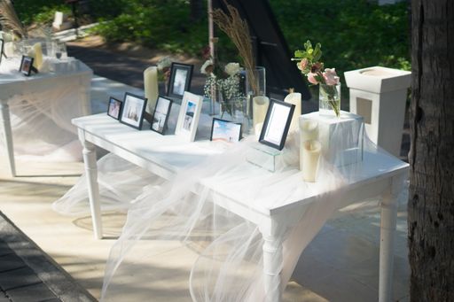 A high angle shot of a white table for wedding photo frames decorated with candles and flowers during daytime