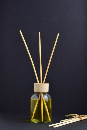 A vertical shot of a container with aromatic liquid and wooden sticks on a dark background