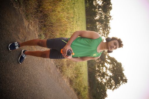 A vertical closeup of the young man in a sports outfit training outside.