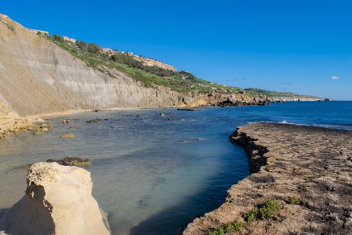 Steep blue clay slopes, with flaking debris forming scree on limestone along the coast of Xatt l-Ahmar, Ghajnsielem, Gozo, Malta, on a sunny day.