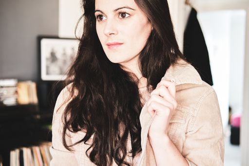 A young woman with brunette hair looking in front of her with a serious face expression