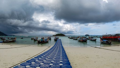 A serene view of a boats in the clear sea in Koh Lipe Thai island on a cloudy day